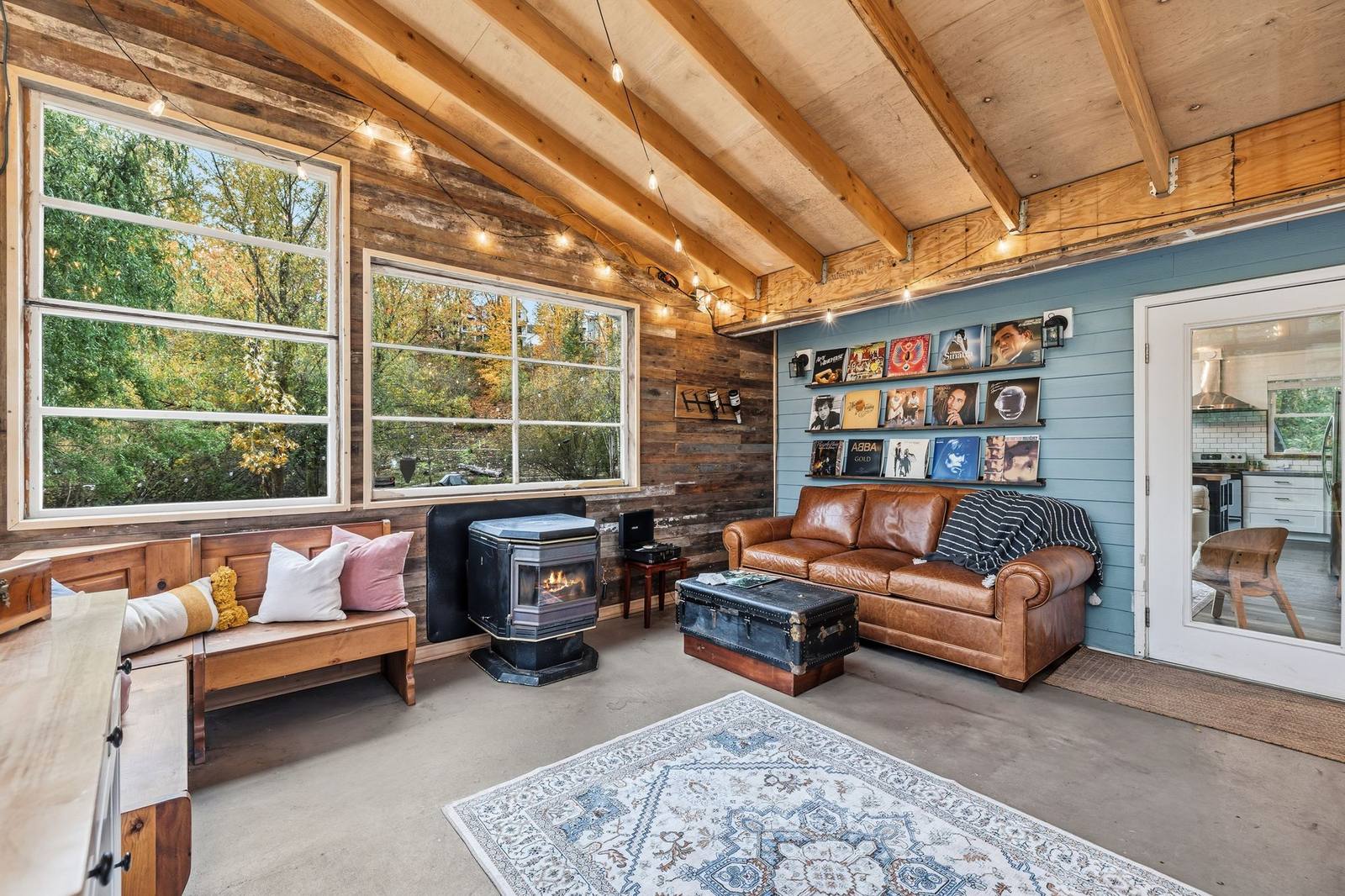 Cozy living room with a leather sofa, wood-beamed ceiling, and wood stove in a Stay Flourish-managed Bothell short-term rental